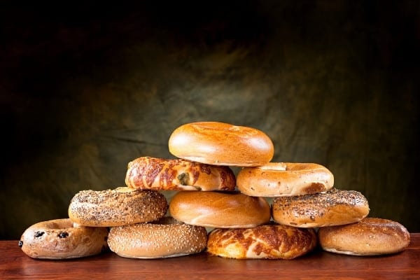 A pyramid of flavored bagels against a black background.