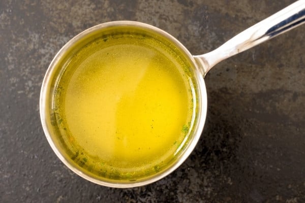 A silver pot containing plain chicken broth resting on a countertop.